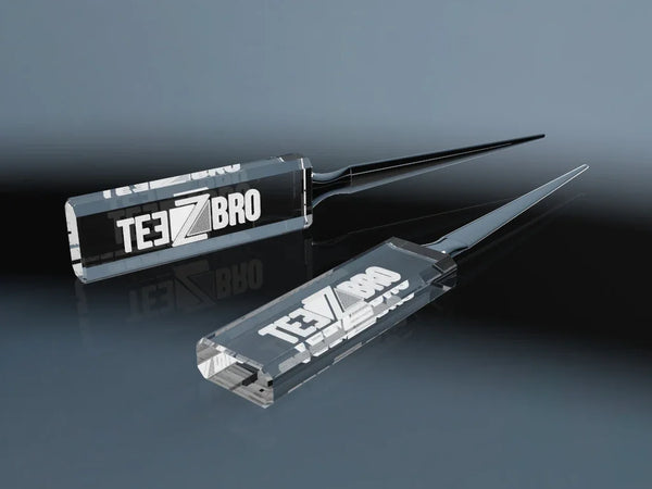 Two crystal glass letter openers with an engraved logo on a reflective surface