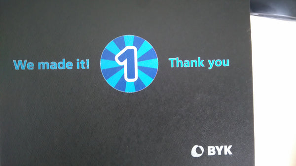 Schwarze Box mit blauem Druck, Zahl 1 und Text We made it! Thank you, Firmenlogo BYK