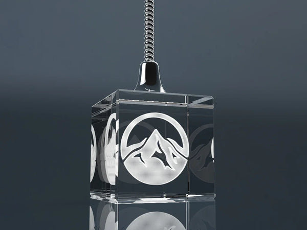 Elegant crystal glass memo holder with an engraved mountain motif on a dark background