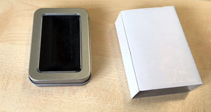 Metallbox für USB-Stick mit Sichtfenster und weißer Karton auf Holzoberfläche