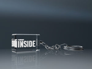 Transparent engraved crystal glass keyring with a metal ring on a grey background