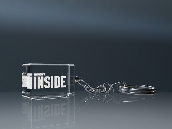 Transparent engraved crystal glass keyring with a metal ring on a grey background